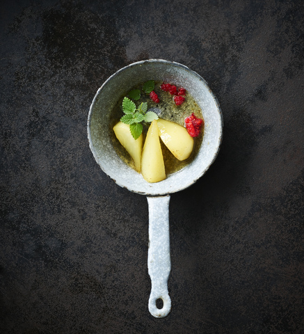 Tonkabohnenbirnen und Himbeeren mit Minze in einem Kochtopf, lizenzfreies Stockfoto