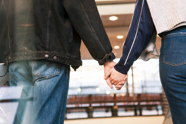 Mittelteil eines jungen Paares, das sich an den Händen hält, während es in einer U-Bahn-Station steht - MASF07084