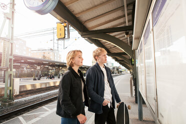 Junges Paar, das auf dem Bahnsteig stehend eine Informationstafel betrachtet - MASF07093