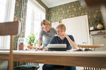 Junges Paar diskutiert über ein Buch, während es am Tisch studiert - MASF07109