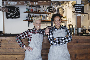 Portrait of smiling female bartenders standing against bar counter - MASF07129