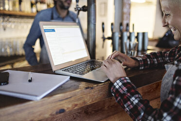 Lächelnder Manager mit Laptop am Bartresen - MASF07132