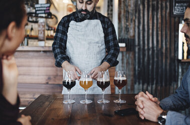 Ein Barkeeper erklärt den Kunden an der Bar verschiedene Biersorten - MASF07141