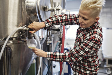 Selbstbewusste Managerin beim Ausschenken von Bier aus einem Lagertank in einer Fabrik - MASF07151