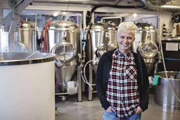 Porträt einer lächelnden Managerin, die mit den Händen in den Taschen in einer Brauerei steht - MASF07166