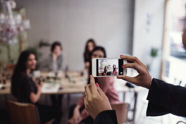 Cropped hands of woman photographing female colleagues sitting at table in perfume workshop - MASF07205