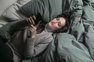 High angle view of woman using smart phone while lying on bed - MASF07265