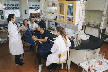 Ein erwachsener Lehrer erklärt jungen multiethnischen Universitätsstudenten im Chemielabor etwas in voller Länge - MASF07320