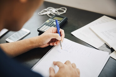 Abgeschnittenes Bild junger männlicher Universitätsstudent, der im Klassenzimmer in ein Buch schreibt - MASF07338