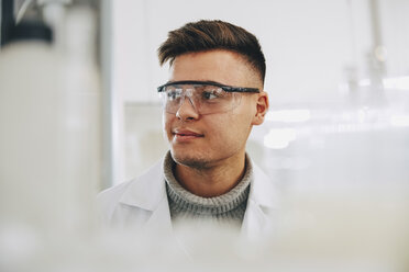 Selbstbewusster junger Chemiestudent mit Brille, der im Labor wegschaut - MASF07349