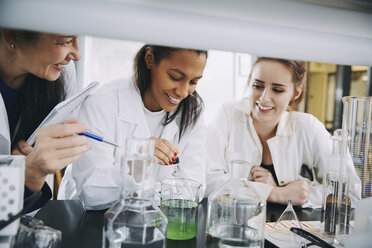 Smiling multi-ethnic university students with mature teacher mixing solution in laboratory - MASF07359