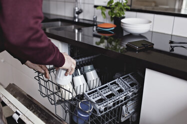 Cropped hands of senior man arranging cup in dishwasher at home - MASF07398