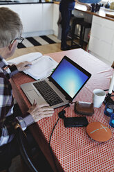 Hohe Winkel Ansicht der pensionierten älteren Mann mit Laptop, während mit finanziellen Rechnungen am Esstisch sitzen - MASF07441