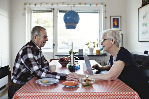 Side view of senior couple holding hands while sitting at dining table - MASF07447
