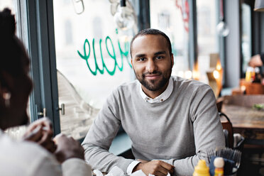 Porträt eines lächelnden Mannes, der mit einem Freund an einem Tisch im Restaurant sitzt - MASF07508