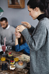 Junge Frau fotografiert Essen auf dem Esstisch im Restaurant - MASF07533