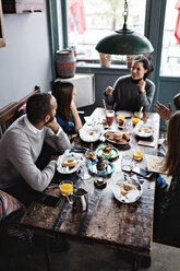 High angle view of friends talking while having food at dining table - MASF07544