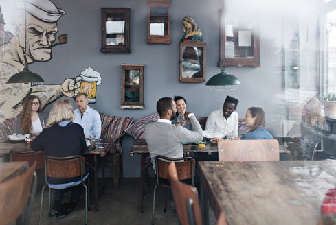 Familie und Freunde beim Brunch im Restaurant, gesehen durch ein Glasfenster - MASF07560