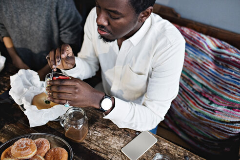Hoher Blickwinkel eines jungen Mannes, der ein Dessert an einem Holztisch im Restaurant isst - MASF07566