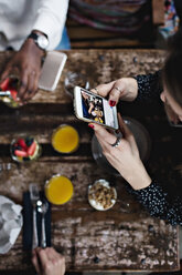 Hoher Blickwinkel einer Frau, die mit ihrem Smartphone am Tisch Essen fotografiert - MASF07569