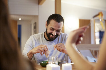 Smiling man eating meal with family at table - MASF07596