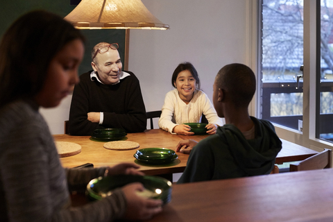 Glückliche Familie im Gespräch am beleuchteten Tisch, lizenzfreies Stockfoto
