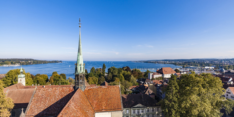 Deutschland, Blick auf den Bodensee mit der Turmspitze des Konstanzer Münsters im Vordergrund, lizenzfreies Stockfoto