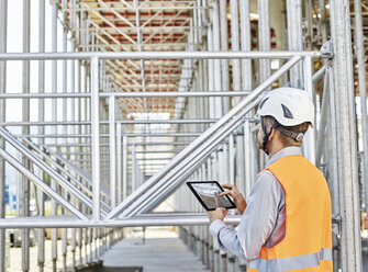 Architect with tablet wearing hard hat on construction site - CVF00339