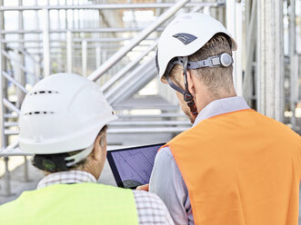 Architect and foreman with tablet wearing hards hat on construction site - CVF00340