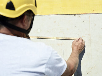 Bauarbeiter mit Zollstock und Bleistift an einer Betonwand - CVF00342
