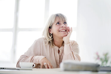 Smiling mature businesswoman at desk looking up - HHLMF00243