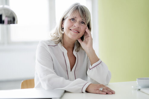 Portrait of smiling mature businesswoman at desk - HHLMF00244