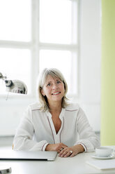 Portrait of smiling mature businesswoman at desk - HHLMF00245