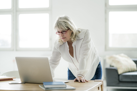 Reife Geschäftsfrau arbeitet am Laptop am Schreibtisch, lizenzfreies Stockfoto