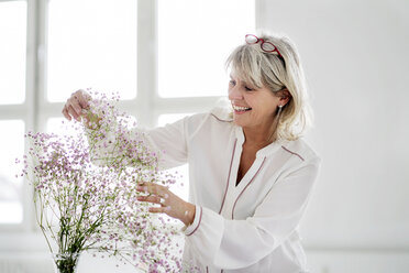 Lächelnde reife Frau, die sich um Blumen kümmert - HHLMF00260