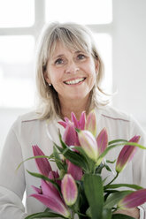 Portrait of smiling mature woman holding bunch of flowers - HHLMF00264