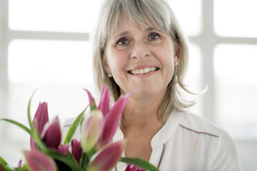 Portrait of smiling mature woman holding bunch of flowers - HHLMF00265