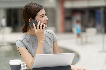 Junge Geschäftsfrau in der Stadt, die vom Straßencafé aus mit ihrem Smartphone telefoniert - ISF00004