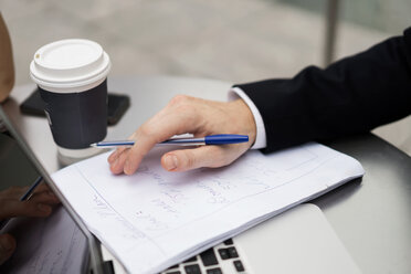 Young city businessman doing paperwork at sidewalk cafe, close up - ISF00009