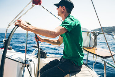 Mid adult man steering yacht near coast, Croatia - ISF00019