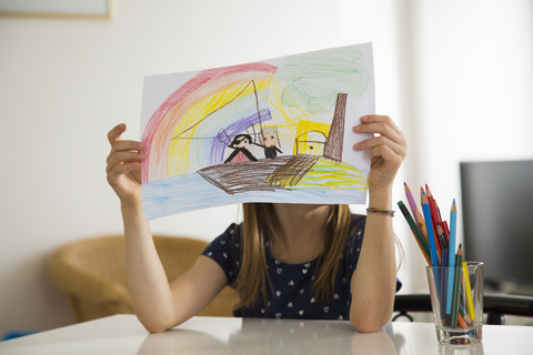 Kleines Mädchen versteckt sich hinter ihrer Zeichnung, lizenzfreies Stockfoto