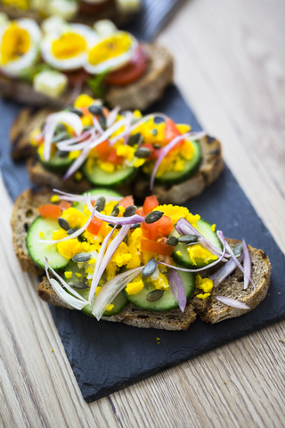 Vegetarisches Frühstück mit Brot, Eiern und Gurkenscheiben auf Schiefer, lizenzfreies Stockfoto