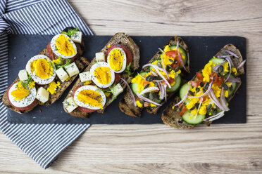 Vegetarisches Frühstück mit Brot, Eiern, Tomatenscheiben und Gurkenscheiben auf Schiefer - GIOF03936