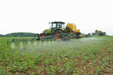 Traktor auf dem Feld beim Sprühen von Pflanzen - CUF00088