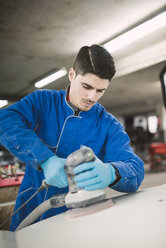 Man polishing the hood of a car in a workshop - RAEF02001
