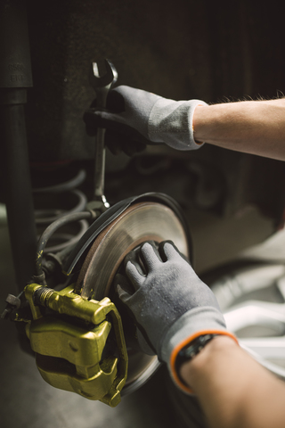Nahaufnahme eines Mechanikers, der den Bremssattel eines Autos in einer Werkstatt repariert, lizenzfreies Stockfoto