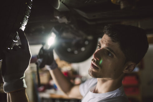 Mechaniker bei der Kontrolle des Unterbodens eines Autos in einer Werkstatt - RAEF02006