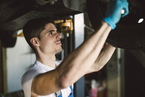 Mechaniker bei Arbeiten am Unterboden eines Autos in einer Werkstatt - RAEF02010