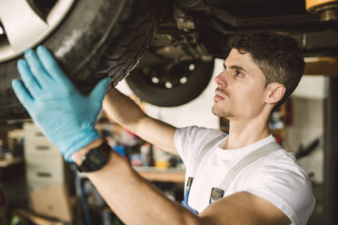 Mechaniker bei Arbeiten am Unterboden eines Autos in einer Werkstatt - RAEF02011