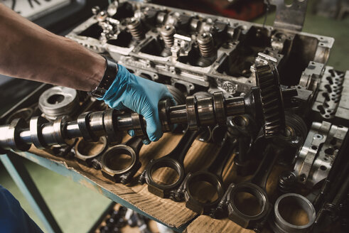 Nahaufnahme eines Mechanikers, der die Kurbelwelle eines Automotors in einer Werkstatt hält - RAEF02013